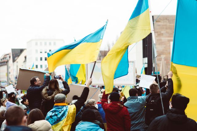 Menschen mit Ukraine-Fahnen; Ein Jahr Ukraine-Krieg: Folgen für Menschen und Wirtschaft