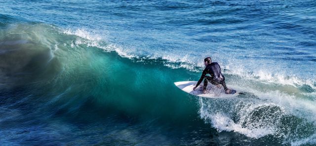 Das Bild zeigt einen Surfer wie er eine Welle reitet.