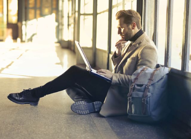 Ein Mann sitzt auf dem Boden mit einem Laptop auf dem Schoß; Rendite: Vergleich und Berechnung
