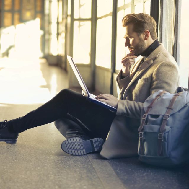 Ein Mann sitzt auf dem Boden mit einem Laptop auf dem Schoß; Rendite: Vergleich und Berechnung