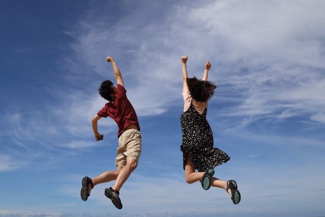 Zwei Menschen springen vor Freude in die Luft.