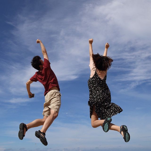 Zwei Menschen springen vor Freude in die Luft.