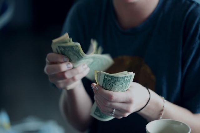 Eine Frau zählt US-Dollar Noten mit ihren Händen.