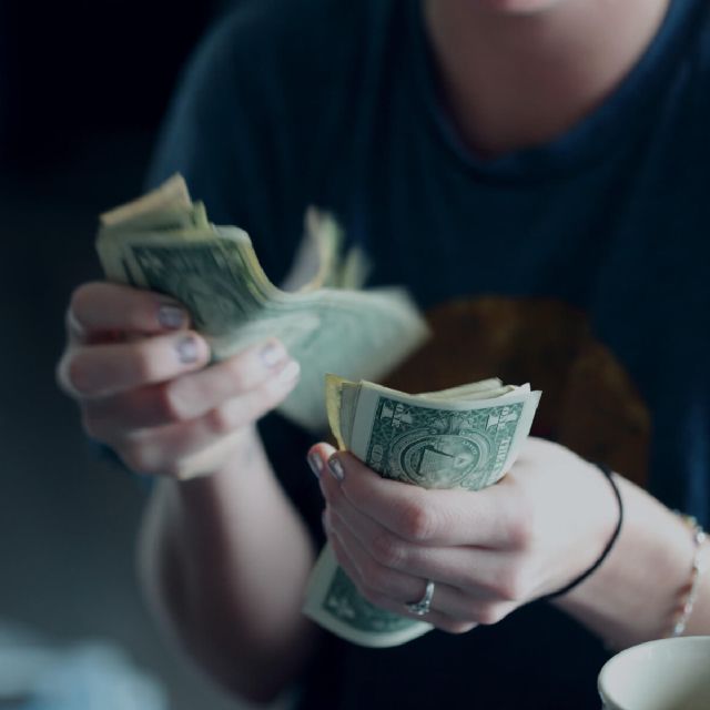 Eine Frau zählt US-Dollar Noten mit ihren Händen.