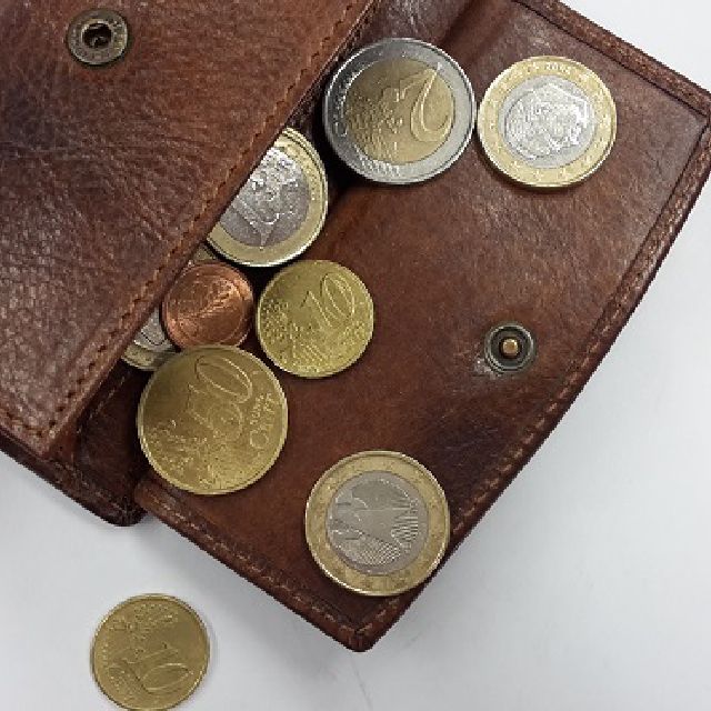 Euromünzen fallen aus einer Geldbörse heraus.