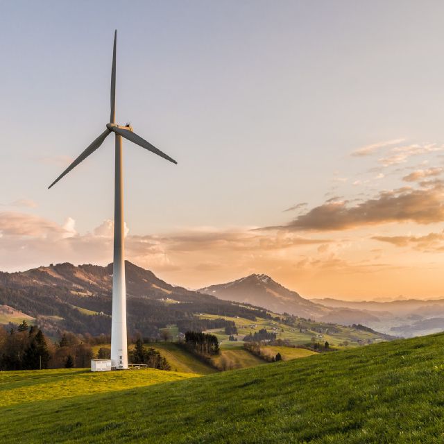 Nachhaltige Geldanlage, mit ETFs: Das Bild zeigt ein Windrad in einer Berglandschaft.