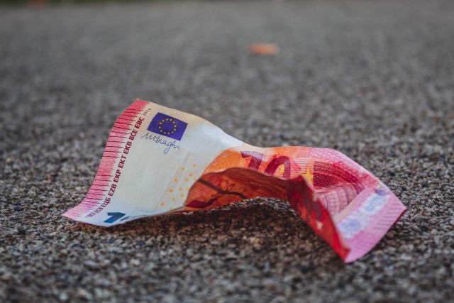 Ein zerknüllter 10 Euro Schein liegt auf der Straße.