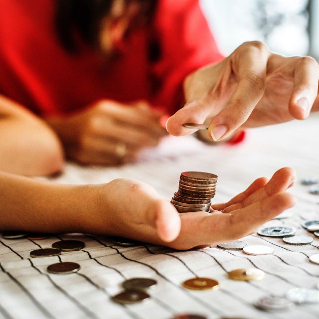 Zwei Personen zählen Geld und stapeln Münzen in der Hand.