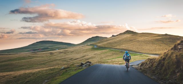 Ein Fahrradfahrer fährt entlang einer bergigen Landschaft.