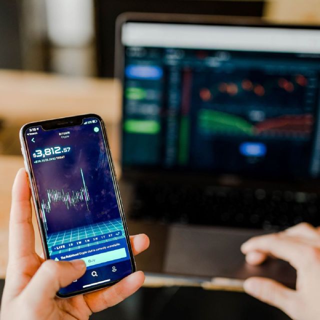 Smartphone und Computerbildschirm mit Aktienkursen an der Börse