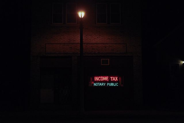 Das Bild zeigt ein Steuerbüro in der Nacht vor einer Laterne.