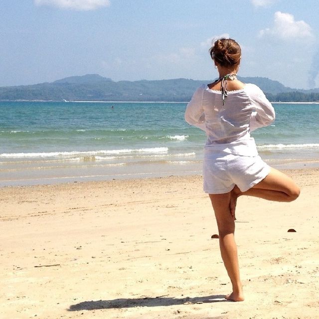 Eine Frau am Strand macht eine Yoga-Pose.