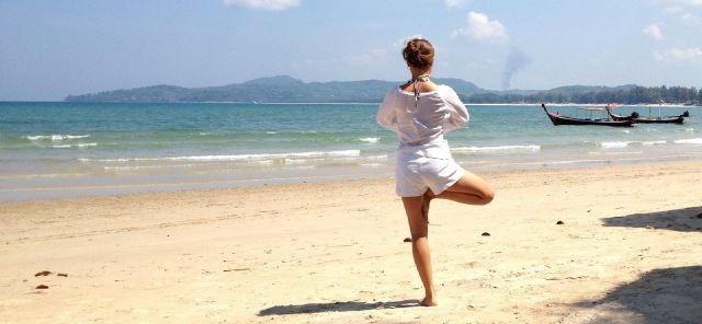 Eine Frau am Strand macht eine Yoga-Pose.