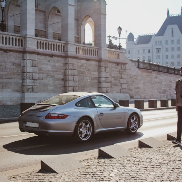 Mann läuft an einem Porsche vorbei; Dax-Änderung: Porsche-Aktie steigt nach Börsengang auf