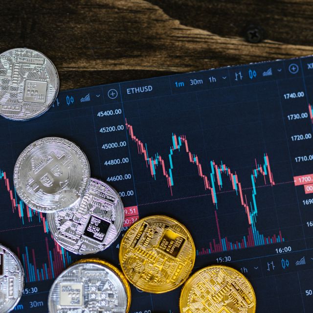 Krypto-Coins vor einem Bildschirm; Was die FTX-Pleite für Krypto-Währungen bedeutet