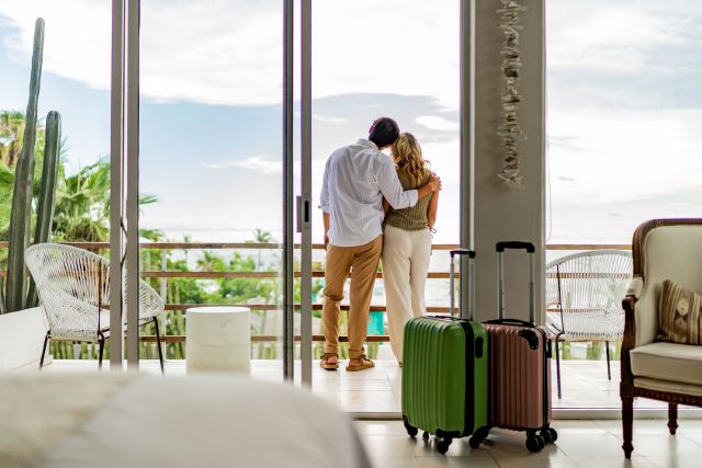 Paar steht am Balkon vom Luxushotel; Warum deutsche Privatanleger mehr investieren sollten 