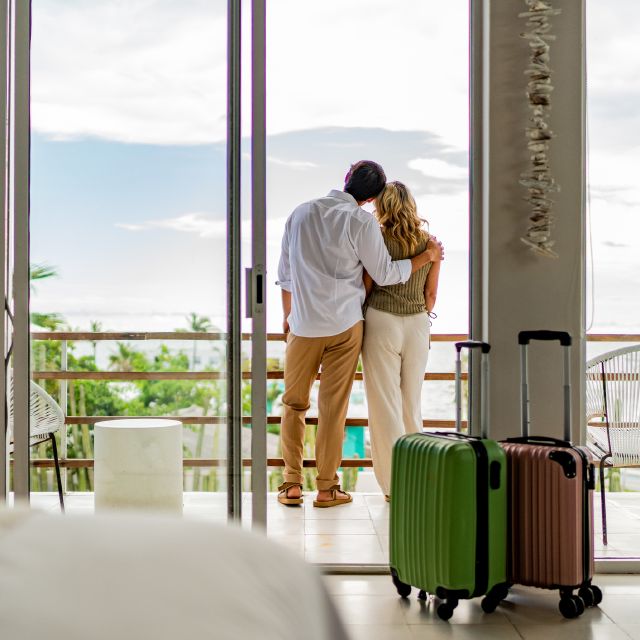 Paar steht am Balkon vom Luxushotel; Warum deutsche Privatanleger mehr investieren sollten 