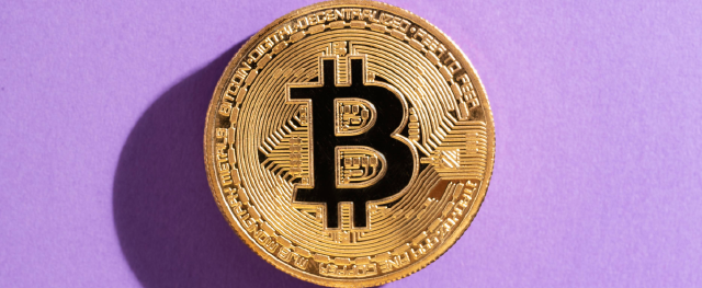 Kryptowährung Bitcoin vor einem lilanem Hintergrund; was sind Kryptowährungen