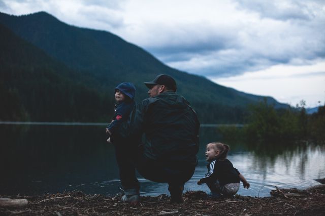 Mann mit zwei Kindern am See; Lebensversicherung: Auszahlung einmalig oder lieber monatlich?