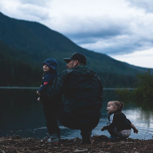 Mann mit zwei Kindern am See; Lebensversicherung: Auszahlung einmalig oder lieber monatlich?