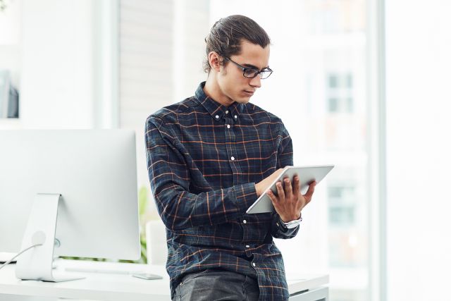 Mann schaut interessiert auf ein Tablet; Diese Tücken gibt es bei der ETF-Auswahl