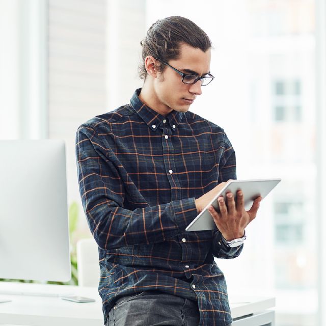 Mann schaut interessiert auf ein Tablet; Diese Tücken gibt es bei der ETF-Auswahl Mann schaut interessiert auf ein Tablet; Diese Tücken gibt es bei der ETF-Auswahl