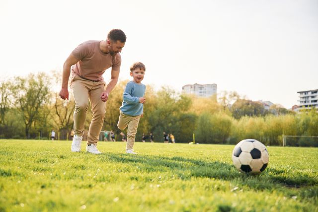 Vater und Kind mit Fußball auf der Wiese; Kinderdepot Vergleich Vor- und Nachteile