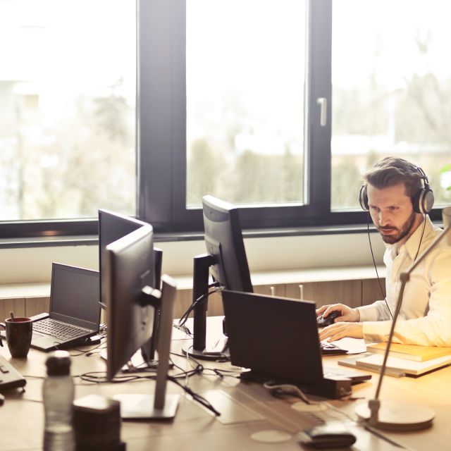 Mann sitzt mit Kopfhörern am Schreibtisch; growney Testsieger bei Transparenz und Kundenservice