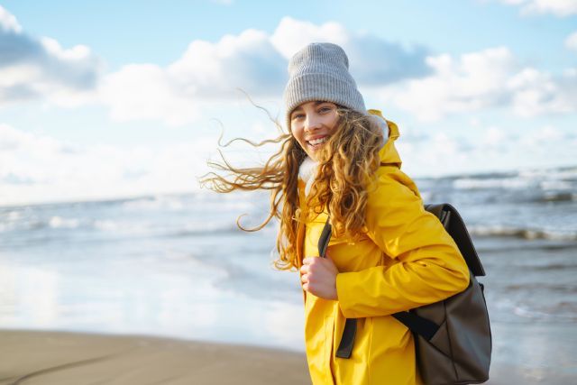 Frau mit wehenden Haaren am Strand: Welche Geldanlage passt zu mir? 