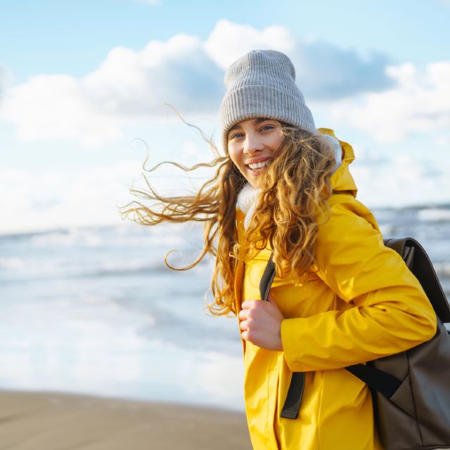 Frau mit wehenden Haaren am Strand: Welche Geldanlage passt zu mir? 