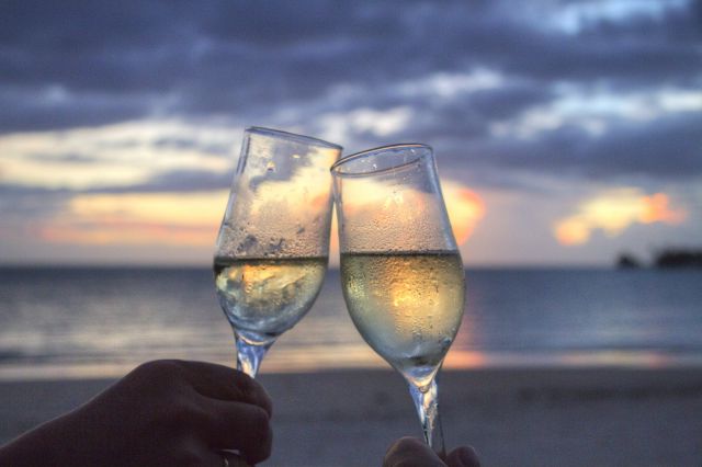 Champagnergläser im Sonnenuntergang am Strand; Wie werde ich Millionär? Millionärsformel mit ETF-Sparplan