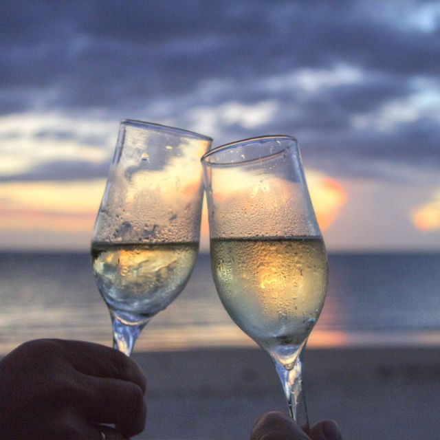 Champagnergläser im Sonnenuntergang am Strand; Wie werde ich Millionär? Millionärsformel mit ETF-Sparplan